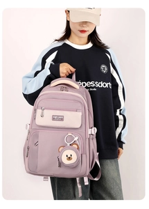 Detailed side view of high-capacity purple nylon backpack with cute bear charm