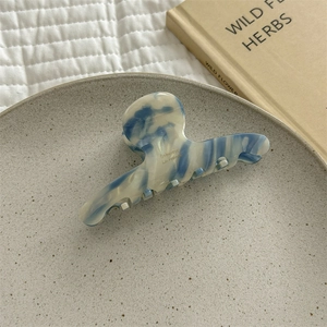 Detail of blue marble acetate hair claw clip with gold brand text on stone tray