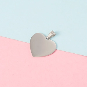 Polished heart-shaped stainless steel pendant on a minimalist pink and blue background