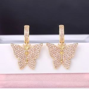 Detailed close-up of gold butterfly earrings with pink cubic zirconia on a display stand