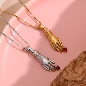 Detail of hand-shaped pendant with red heart gemstone on 18K gold plated chain
