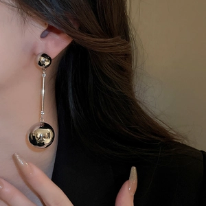 Side view detail of silver ball drop earrings with metallic finish on model