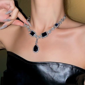 Detail of elegant silver necklace with square and teardrop blue stones on a model