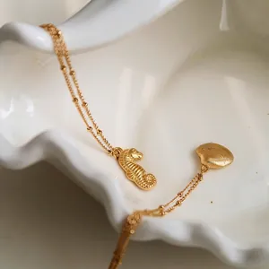 Golden sea horse and seashell pendant necklace on white ceramic tray