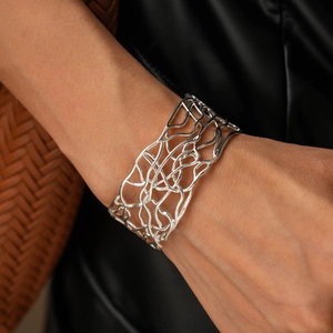 Close-up of a silver intertwined hollow cuff bracelet with organic vine-like metal texture