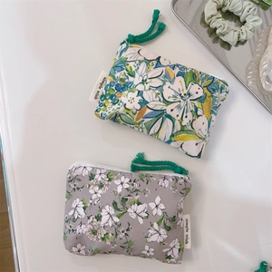Detailed close-up of floral cotton pouches with white zippers and green pull cords