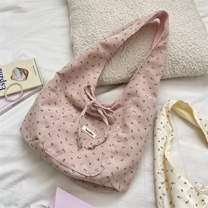 Detail of light pink corduroy hobo bag with floral pattern and decorative bow tie