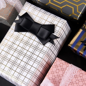 Premium black and gold geometric gift wrapping paper with elegant satin ribbons and lace