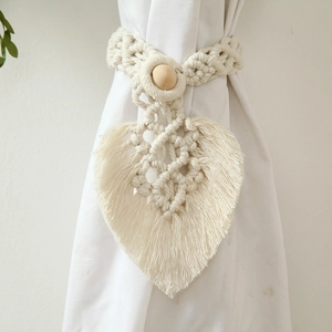 Detail of hand-woven cotton curtain tieback featuring a leaf design and wooden button