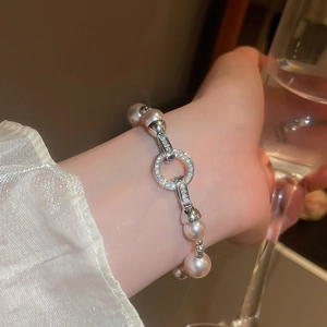 Bracelet élégant en perles avec breloque zircone au poignet près d'un verre