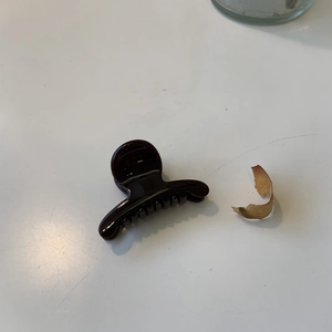 Détail d'une pince à cheveux en résine marron foncé avec finition brillante sur blanc