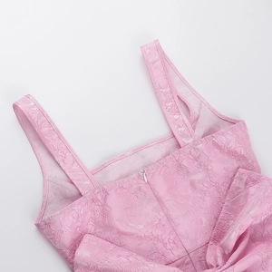 Détail de la robe rose en jacquard montrant fines bretelles, zip et grand nœud