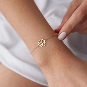 Elegant gold lotus flower charm bracelet on female wrist featuring openwork geometric design