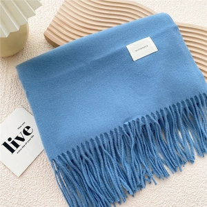 Flat lay of soft blue tassel scarf with fine cashmere-like texture on textured background