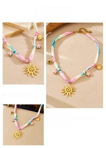 Détail du collier bohème avec pendentif soleil et ruban en soie rose et fleurs