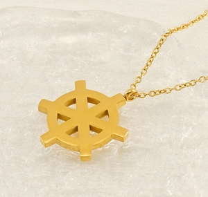 Detail of 18K gold plated ship wheel pendant on a delicate chain over ice texture