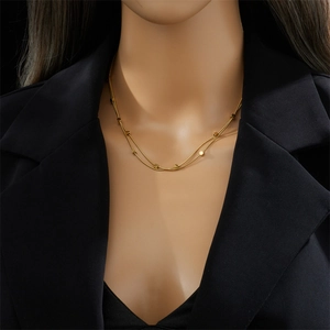 Detail of gold double-layer chain necklace with square beads on a model