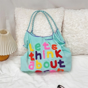 Detail of mint green canvas tote with let's think about chenille patch and braided handles