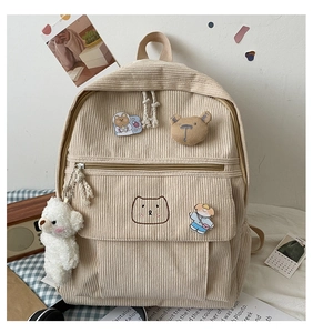 Detalle de la mochila de pana beige con parches de ositos y un suave colgante de peluche