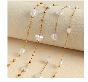 Detailed close-up of 18k gold chain with irregular pearls and butterfly accents