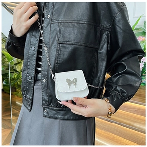 Close-up of white embossed mini saddle bag with silver butterfly buckle and chain strap