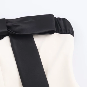 Dettaglio del fiocco in raso nero su un abito a fascia color crema con cuciture fini