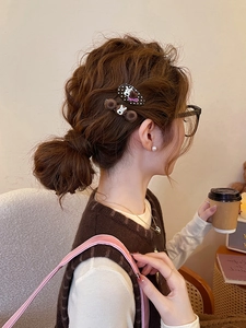 Detail view of brown flocking polka dot puppy hair clips worn on the side of wavy hair