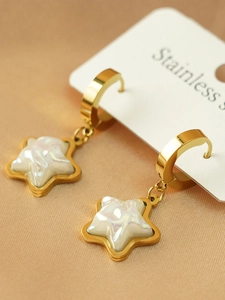 Macro view of gold-plated stainless steel star earrings with iridescent white inlay