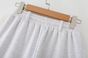 Detail of light gray knitted sweatpants showing elastic waistband and belt loops texture