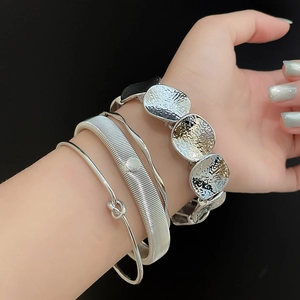 Detailed macro view of four silver irregular textured stackable spring open bracelets