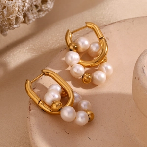 Gros plan sur des boucles d'oreilles en U dorées avec perles d'eau douce fines