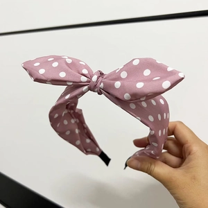 Detailansicht eines rosa Stoffstirnbands mit weißen Punkten und Hasenohr-Knoten-Stil