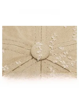 Macro detail of khaki cotton baseball cap top button with heavy stitching and distressed fabric