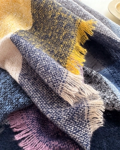 Close-up of soft plaid scarf showing colorful knit texture and fringe details