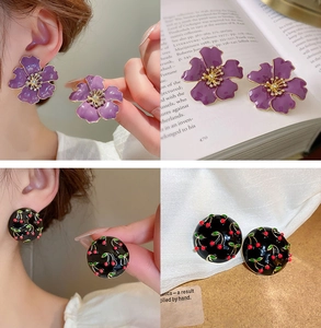 Detail of vintage purple flower and black cherry earrings on model and texture