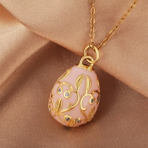 Pink enamel egg pendant with gold vine patterns and sparkling gems on silk background