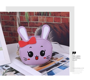 Detail shot of purple rabbit crossbody bag with red bow and silver woven strap