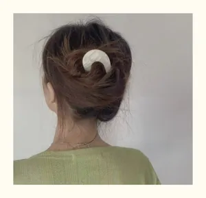 Close-up of white acetate U-shape hair pin with marble texture in an elegant bun