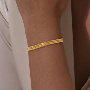 Close-up of triple-layered golden snake chain bracelet on wrist showing metal texture