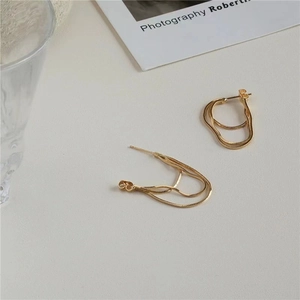 Close-up of golden multi-layer snake chain earrings with a fluid textured design