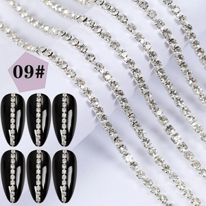 Detail of silver nail art chain with square rhinestones applied on black almond nail tip