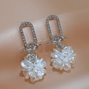Elegant floral drop earrings with white crystals and pearls on beige satin background