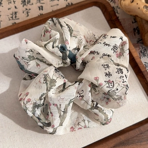Detail of cream silk scrunchie with ink wash calligraphy on a vintage wooden tray