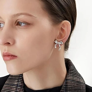 Elegant silver bow stud earrings with sparkling crystals worn by a female model