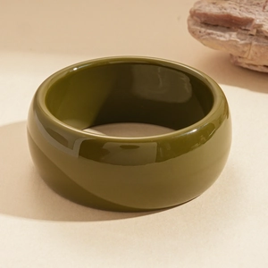 Close-up of olive green resin bangle with smooth glossy finish and minimalist aesthetics