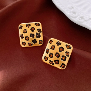 Gros plan de boucles d'oreilles léopard vintage avec strass orange sur de la soie