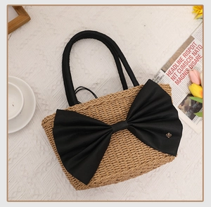 Detailed close-up of straw woven handbag with large black bow and round handle