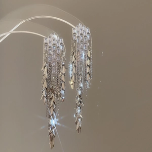 Detailed view of silver tassel earrings with rectangular zircons and metal leaves
