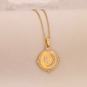 Detail view of a gold star and moon pendant necklace with crystals on beige background