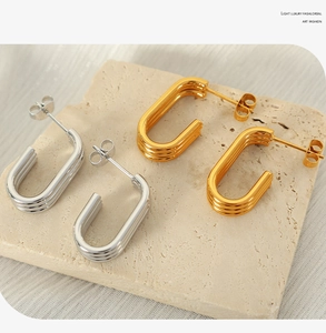 Detail view of multi-layered gold and silver C-shaped textured stud earrings on stone